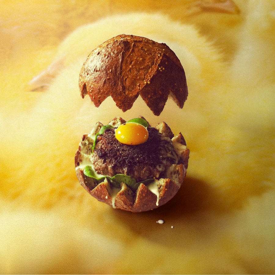 the-fricocotte-burger-has-a-nest-of-spinach-a-small-burger-patty-and-an-egg-yolk-the-floating-bun-was-obviously-photoshopped-in
